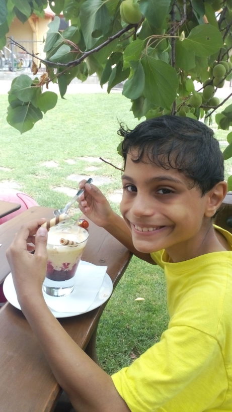Smějící se chlapec jí zmrzlinový pohár